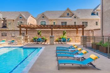 A pool with sun loungers and a building in the background.